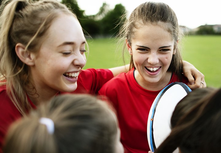 Girls in red team shirts celebrating a victory on the field